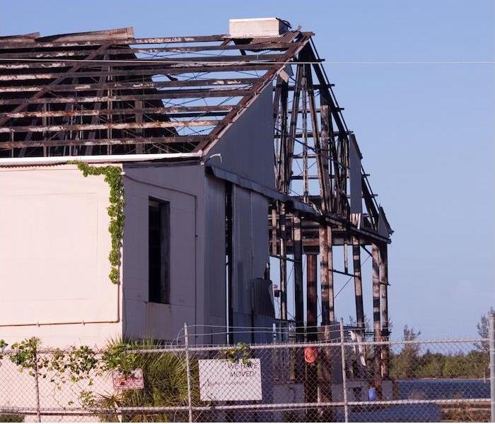 a large commercial building with extensive damage to roof and siding